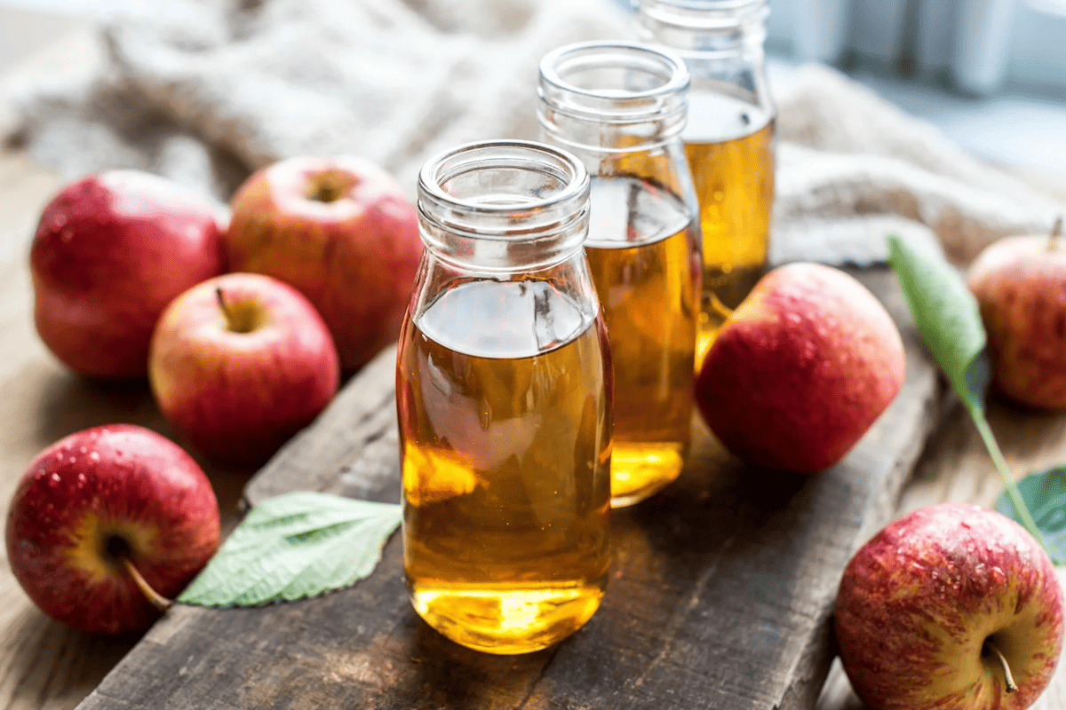 apple cider vinegar in a glass bottle with fresh apples