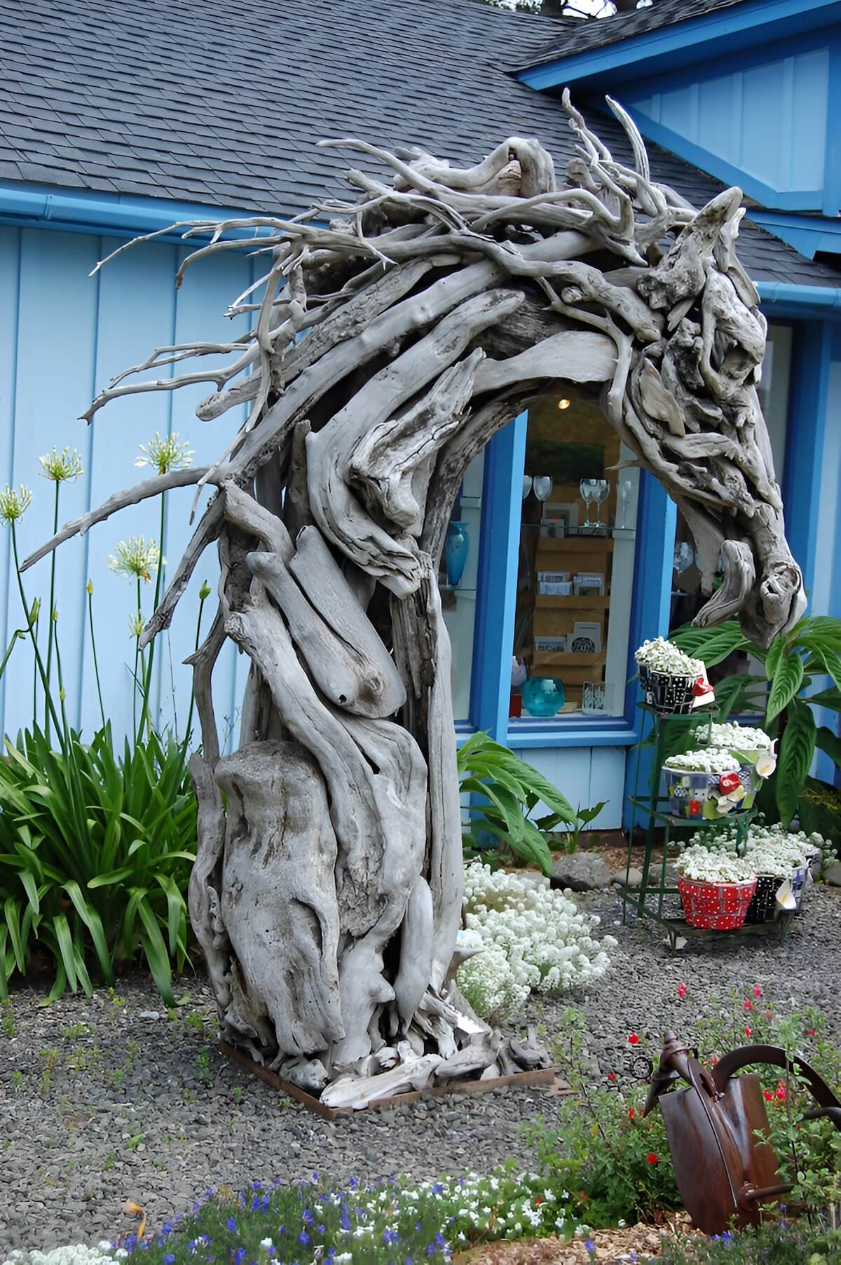 Horse sculpture made from driftwood displayed in a garden setting with organic shapes and textures